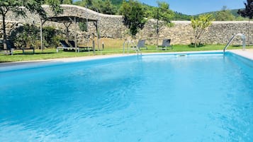 Una piscina al aire libre de temporada, sombrillas, tumbonas