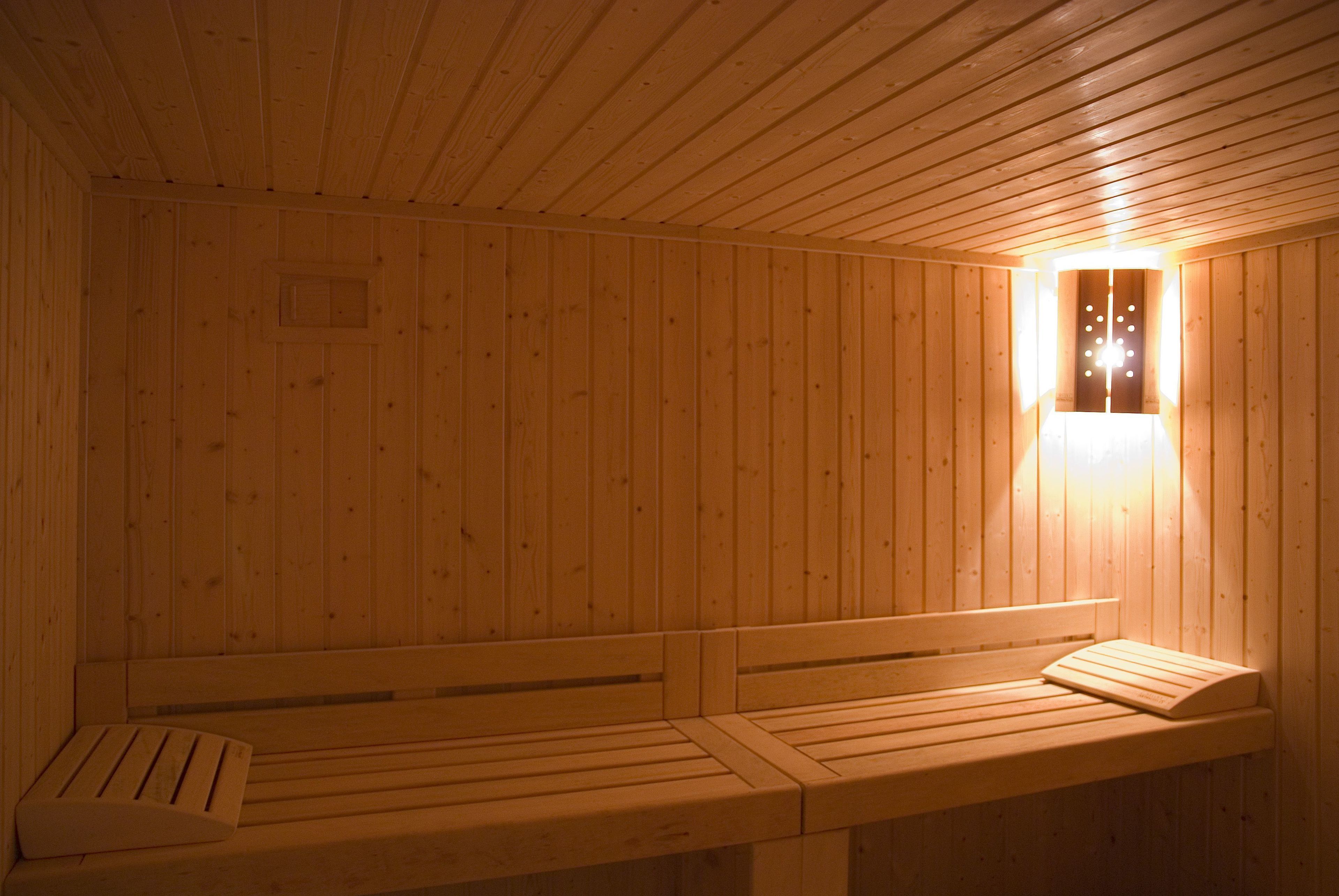 Una sauna de madera con bancos y una lámpara fijada a la pared.