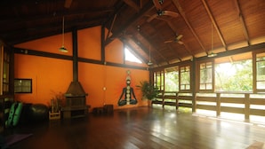 Een ruime kamer met een hoge plafond, houten balken en grote ramen voor natuurlijk licht.