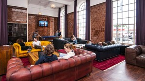 A spacious lobby with leather sofas, a billiards table, and a TV mounted on the wall. - Rest Up London - Hostel (London)