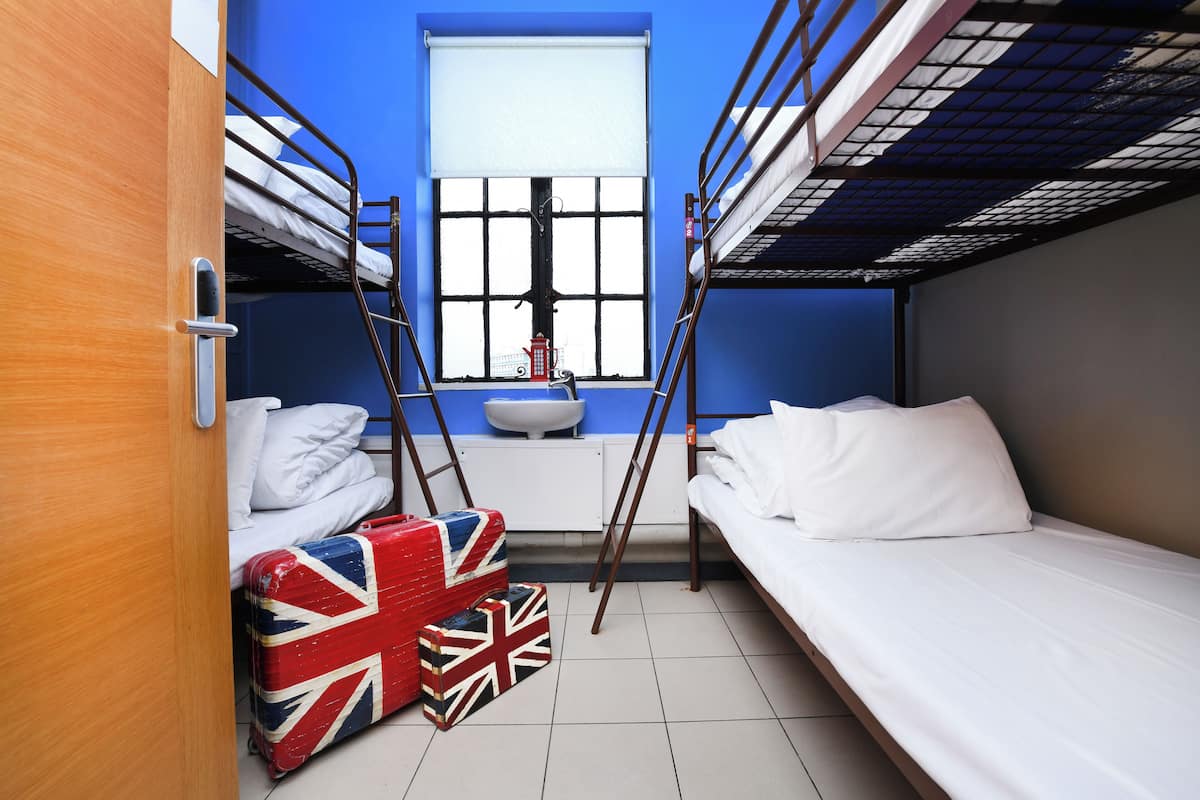A bunk bed room with a window, a sink, and a suitcase with a Union Jack design.