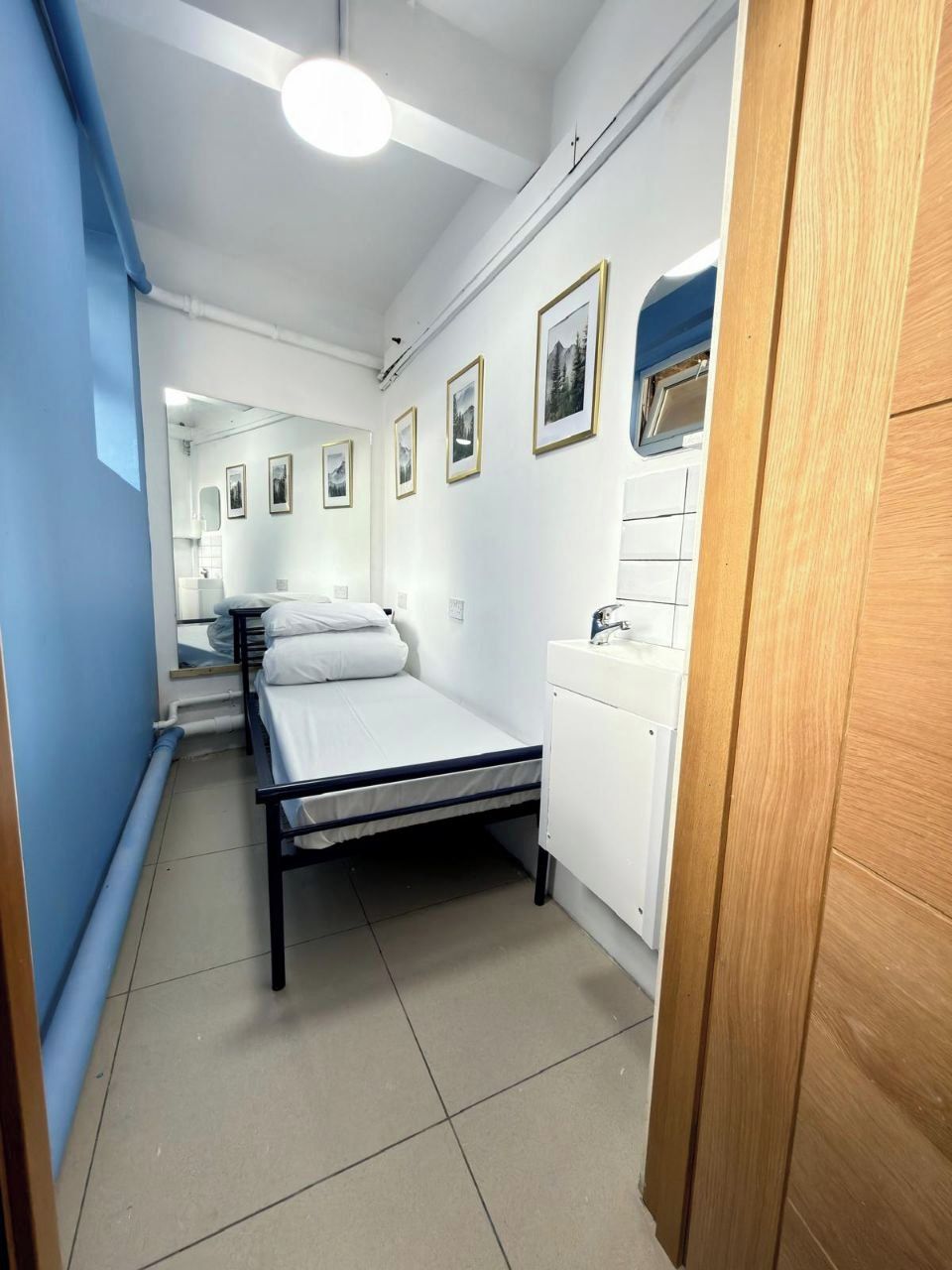A room with a bed, a sink, and framed pictures on the wall.
