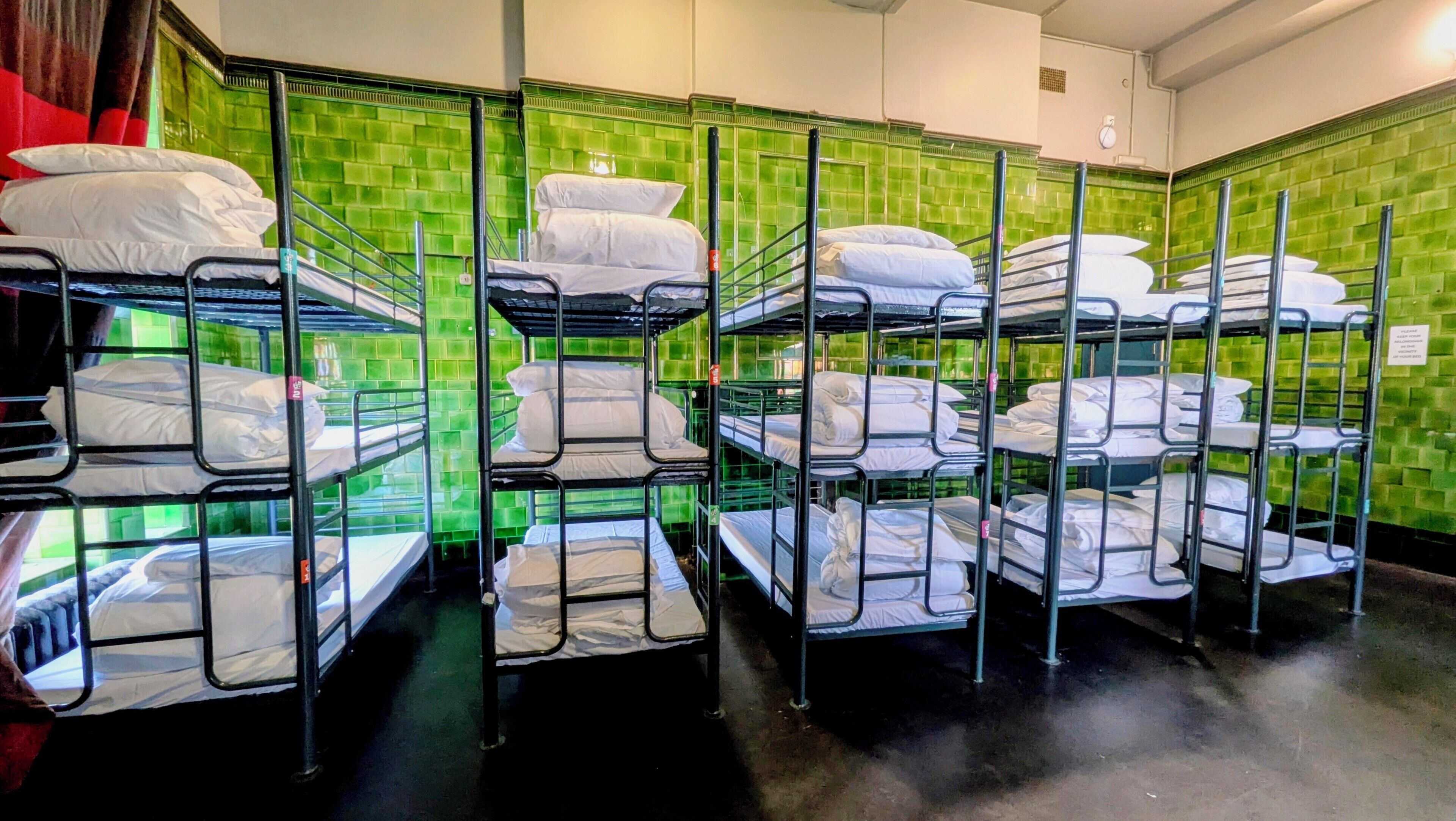 Camas literas dispuestas en una habitación tipo dormitorio con paredes de azulejos verdes.