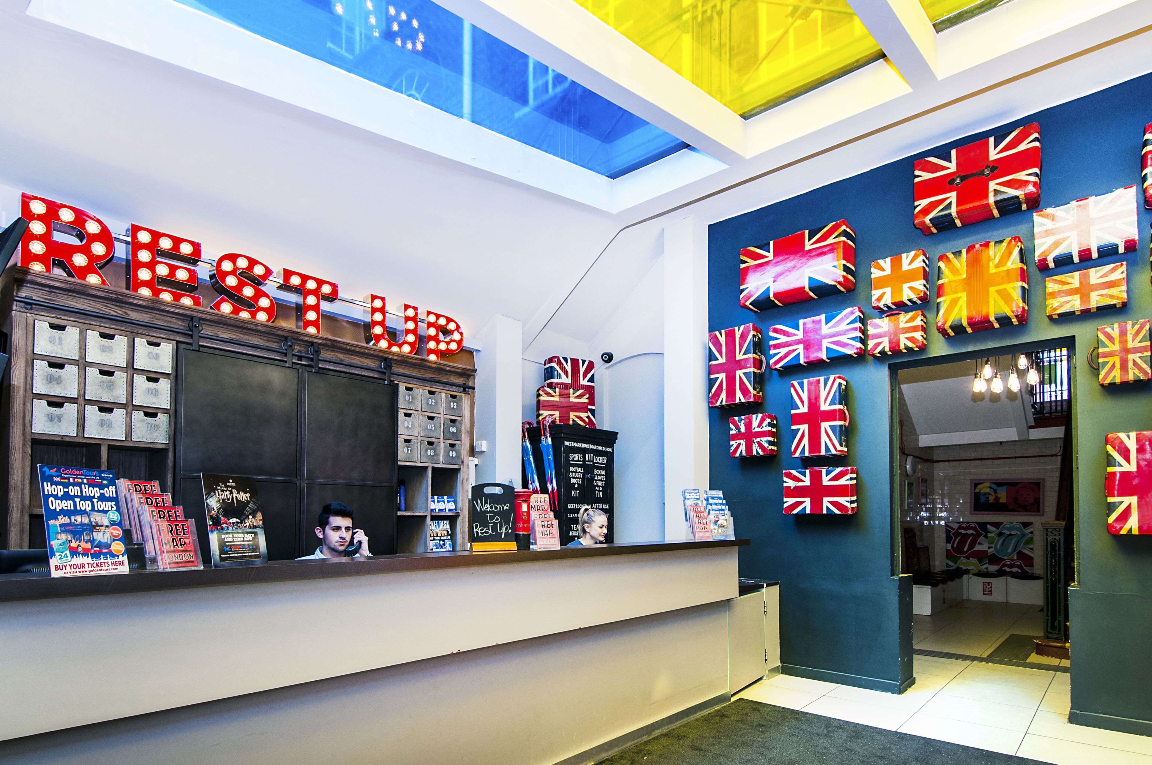 A reception area with a 'Rest Room' sign, a counter with various items, and a wall decorated with multiple British flags.