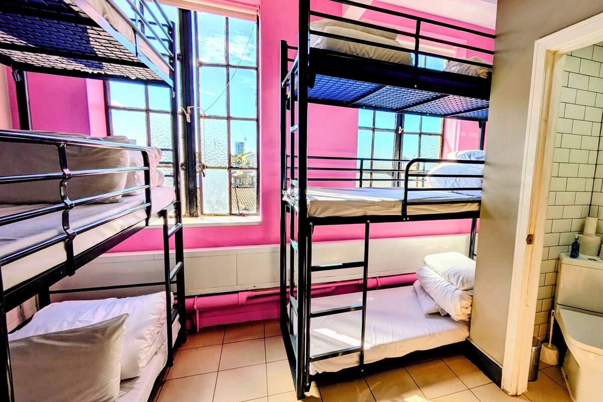 A dormitory room with bunk beds, a window, and a bathroom with a toilet and sink.