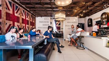 A bar with a Union Jack wall mural, a chandelier, and a bar counter with stools.