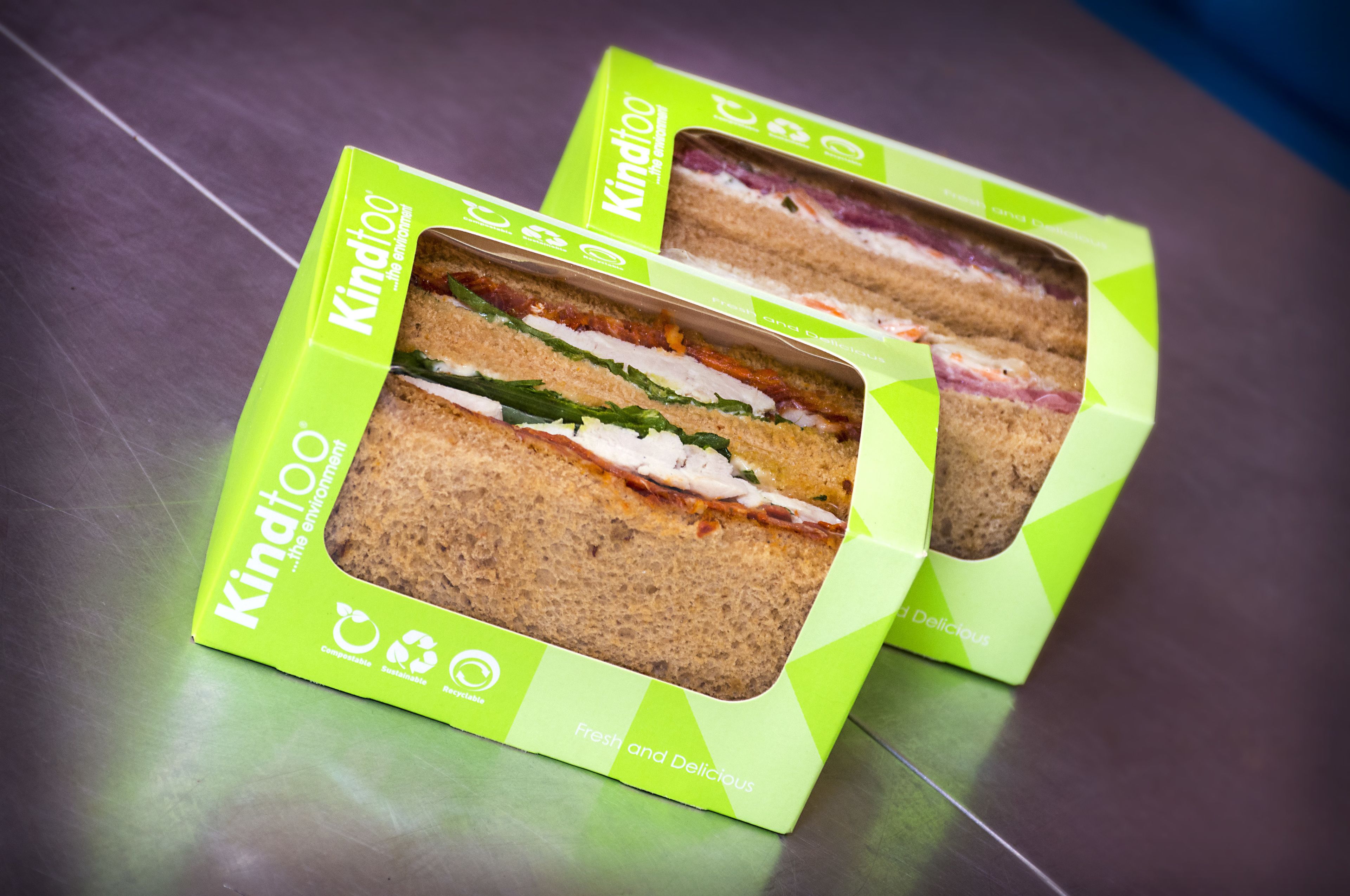 Two sandwiches in green packaging with visible fillings.