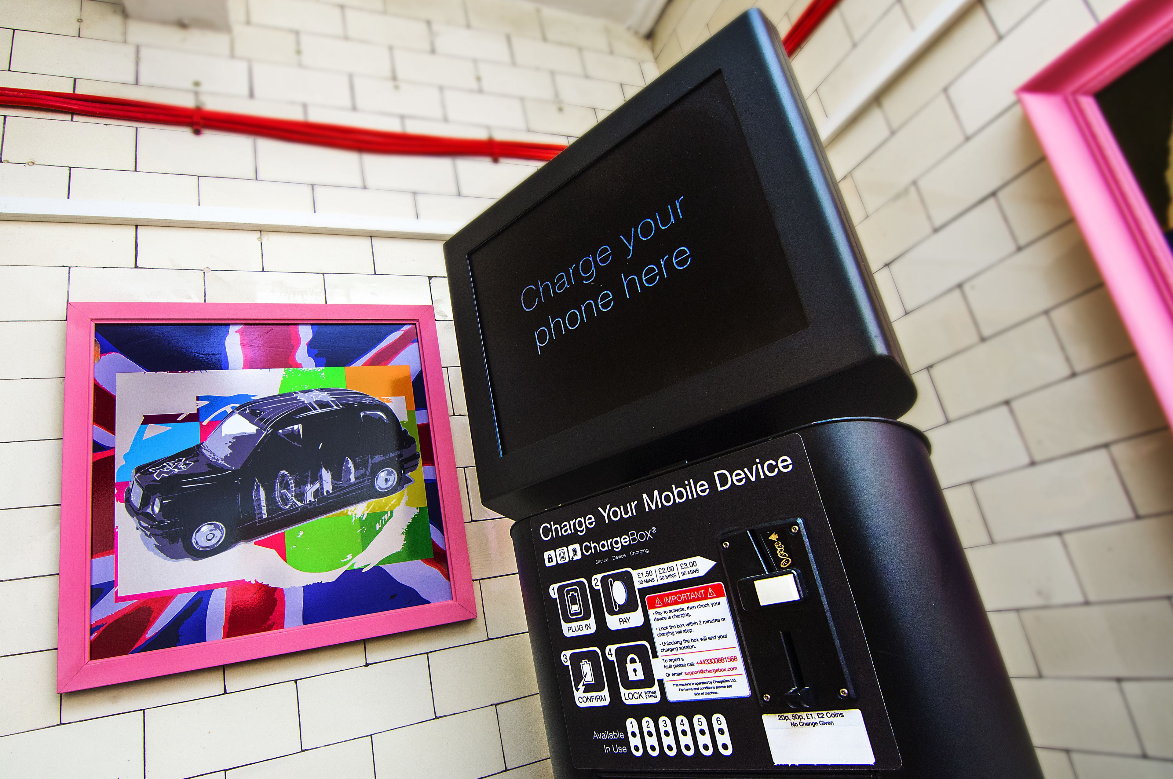A ChargeBox charging station with a colorful artwork on the wall behind it.