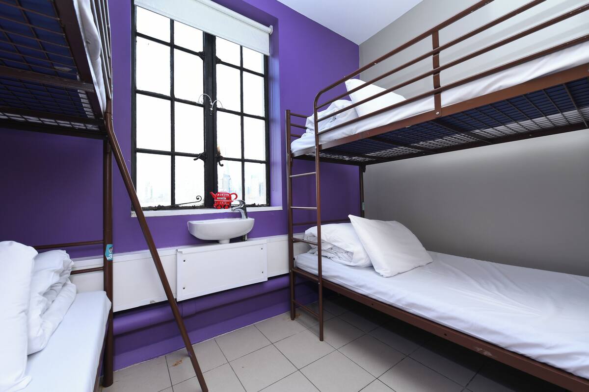 A bunk bed room with a window, a sink, and a white cabinet.