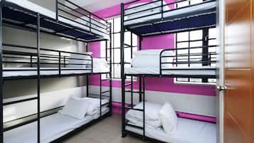 A dormitory room with bunk beds, pink walls, and a window.