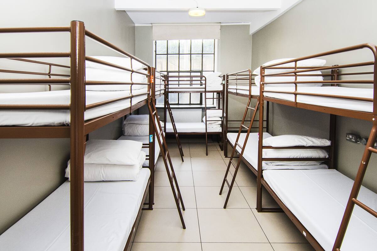 A dormitory room with bunk beds arranged in a row.