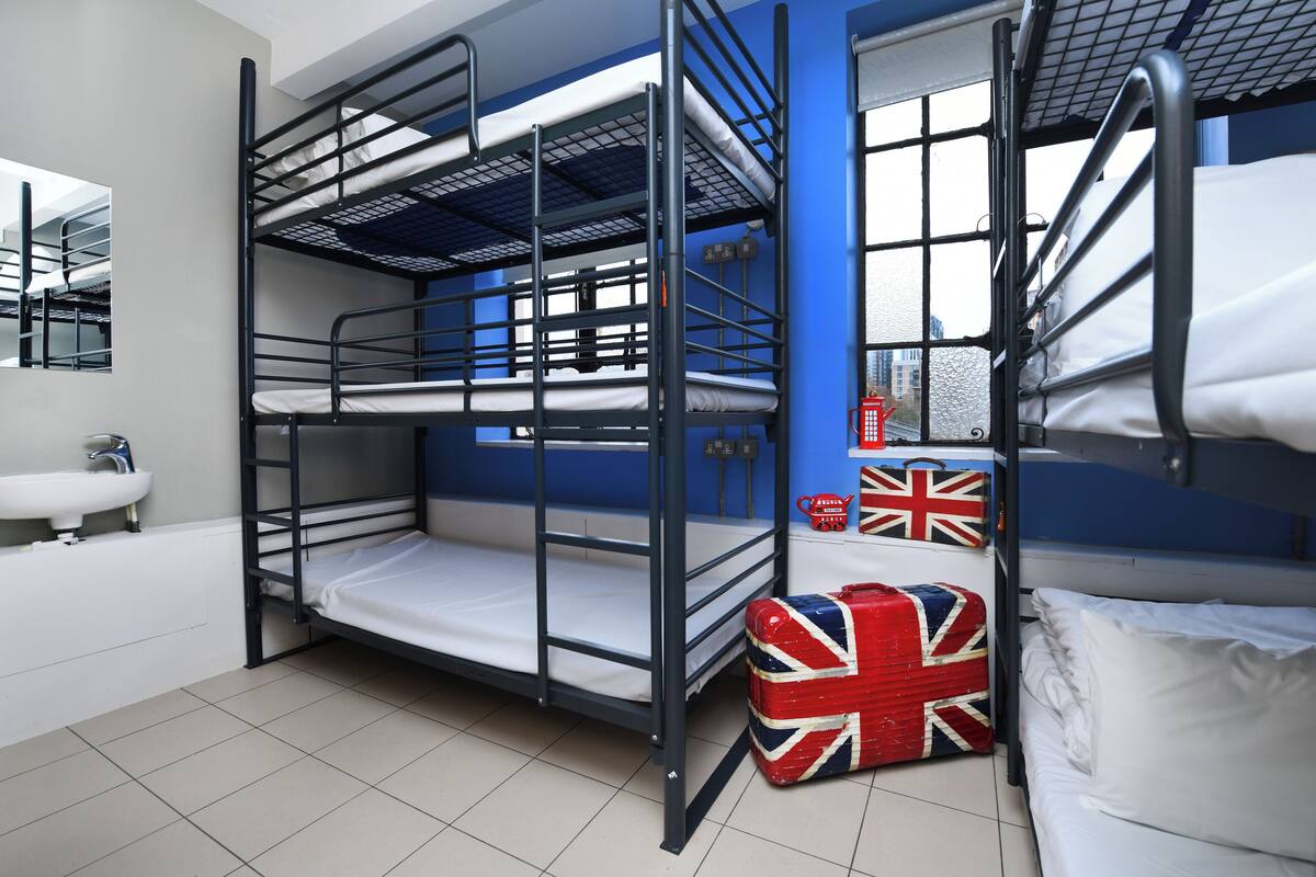 A bunk bed room with a sink and a suitcase with a Union Jack flag.