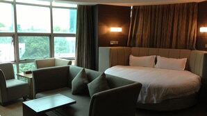 A hotel room with a large bed, two armchairs, a small table, and a window with curtains. - GreenTree Alliance Shenzhen Shekou Sea World Hotel (Shenzhen)