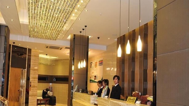 A hotel reception area with a marble counter, a chandelier, and a seating area with a person. - GreenTree Alliance Shenzhen Shekou Sea World Hotel (Shenzhen)