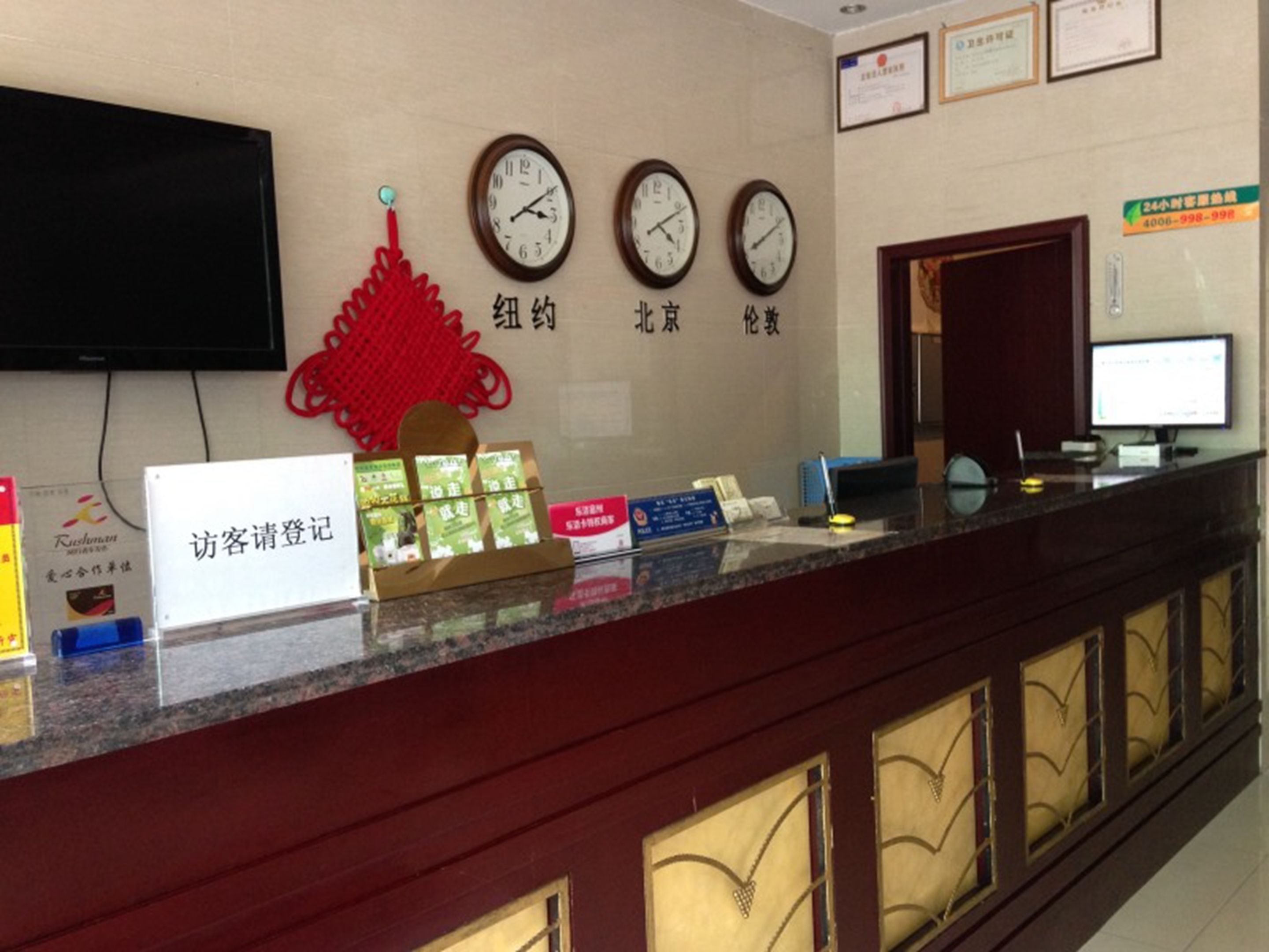 A reception desk with clocks, a red decorative item, and a sign for guest registration.