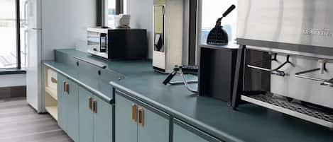 A kitchen with a large window, a microwave, a refrigerator, and a coffee machine.