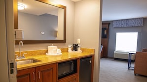 A compact kitchen with a sink, microwave, and coffee maker.