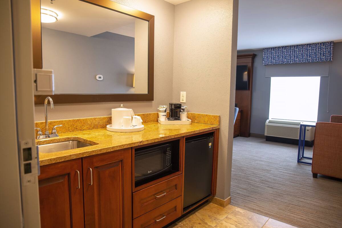 A compact kitchen with a sink, microwave, and coffee maker.