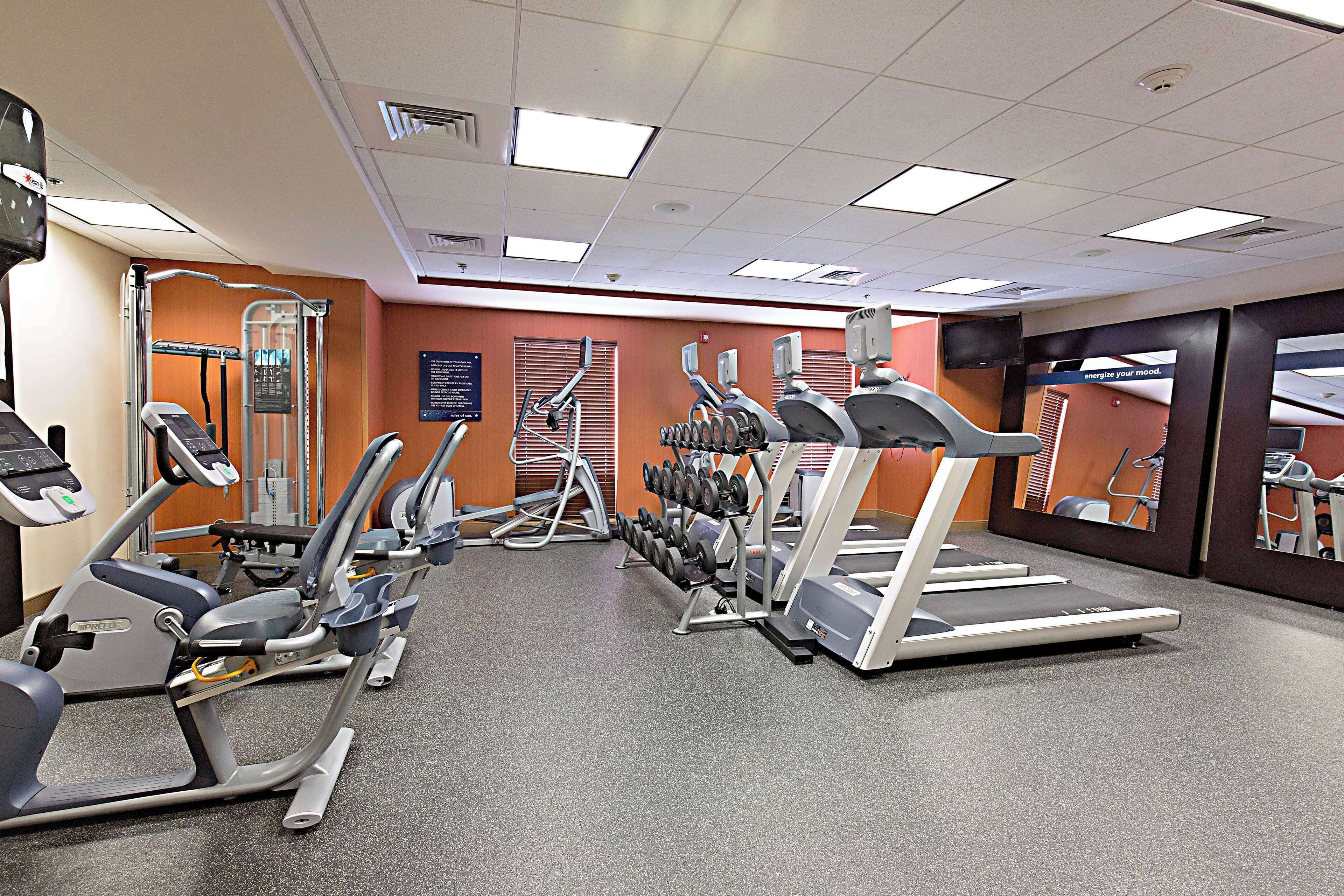 A gym with treadmills, elliptical machines, and weight benches.
