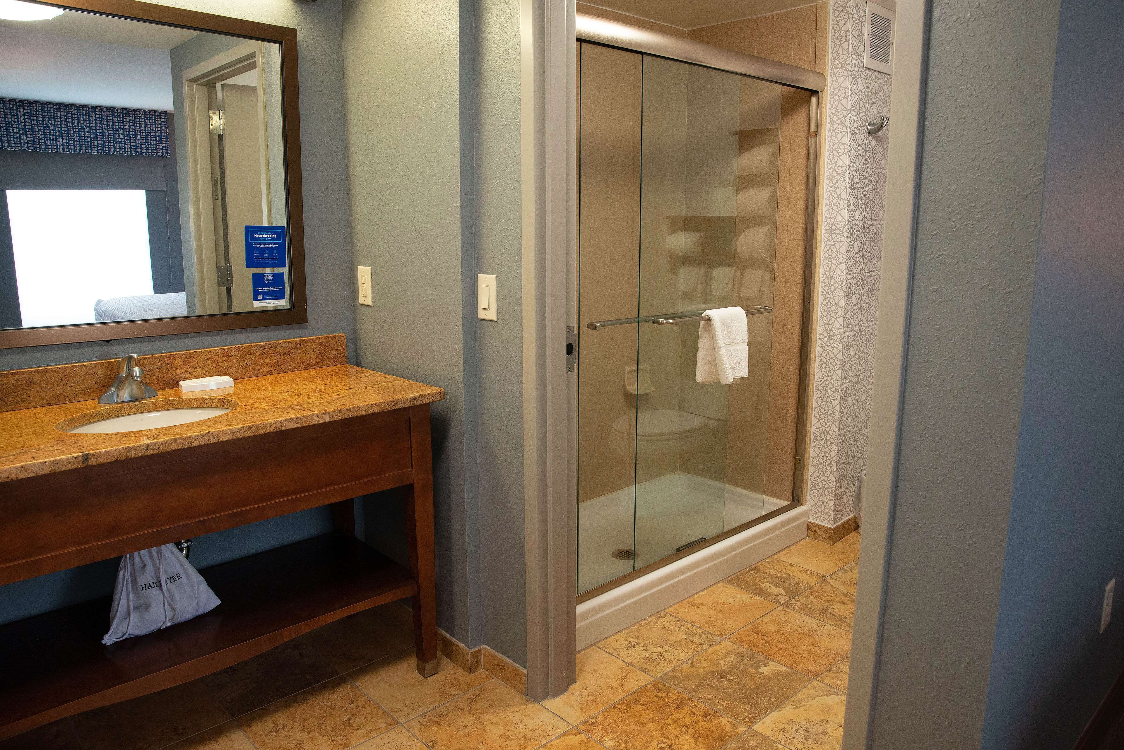 A bathroom with a sink, mirror, and glass shower enclosure.