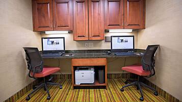 A small office with two desks, two chairs, a printer, and wooden cabinets.