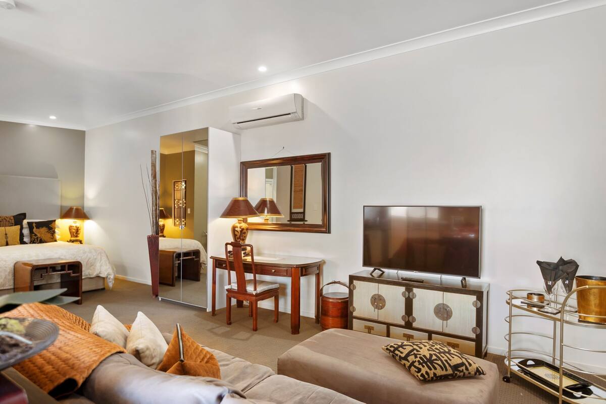 Una habitación de hotel con cama, escritorio con silla, televisión y sofá.