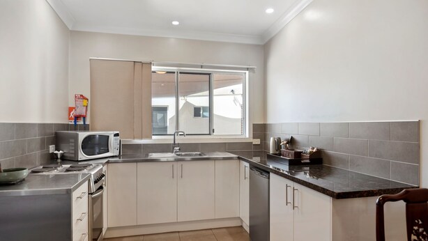 A modern kitchen with white cabinets, a microwave, a stove, and a sink. - 53 on Victoria (Warwick)