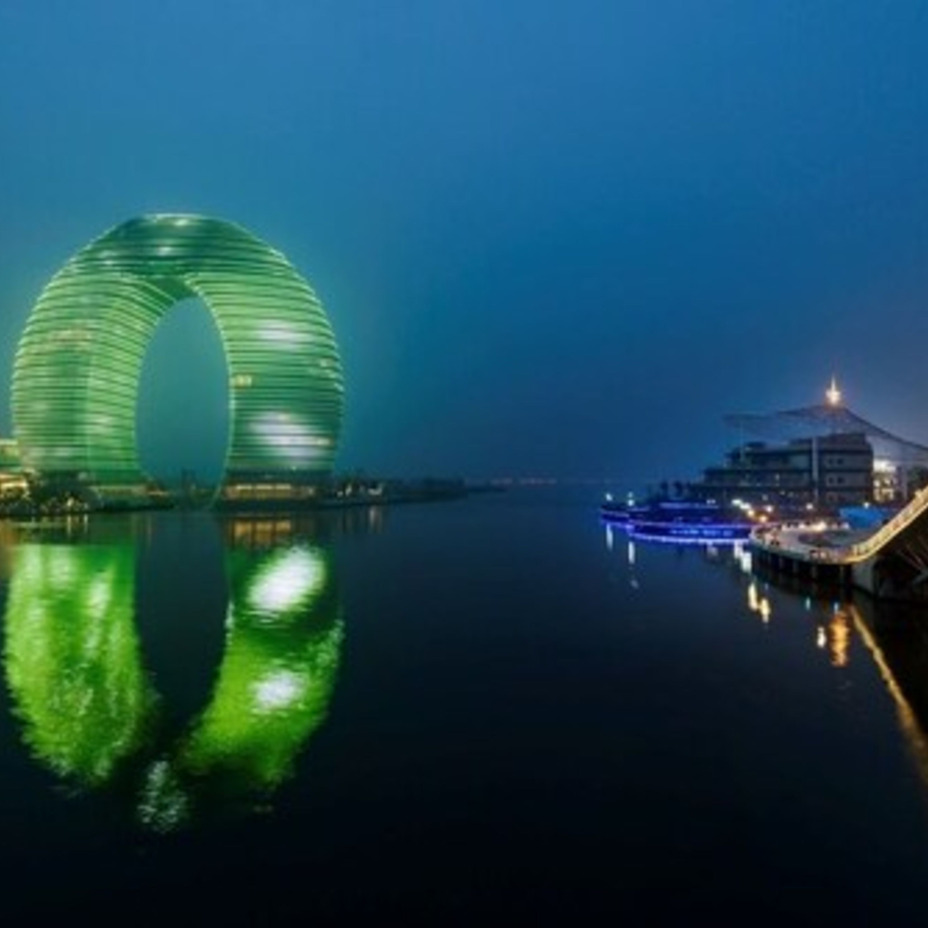 Um edifício moderno com design circular refletindo na água.
