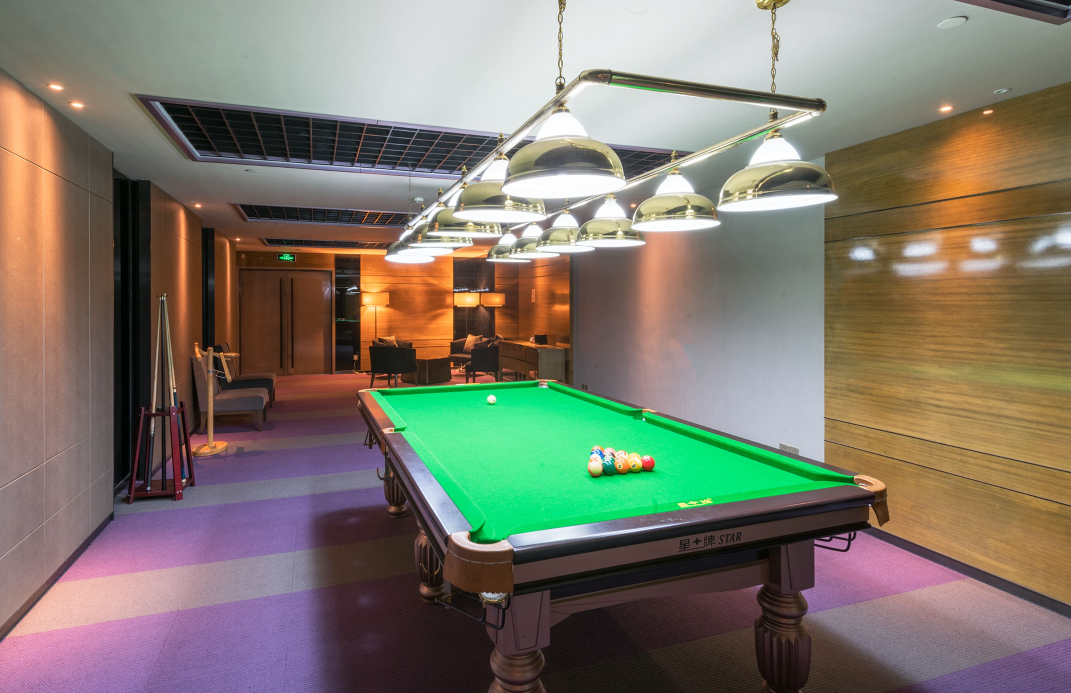 A pool table with balls, overhead lighting, and a billiard cue rack.