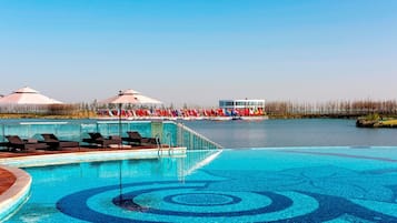 Una piscina techada, una piscina al aire libre, sombrillas