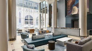 Een moderne lobby met zithoekjes, grote ramen en een groot abstract schilderij.