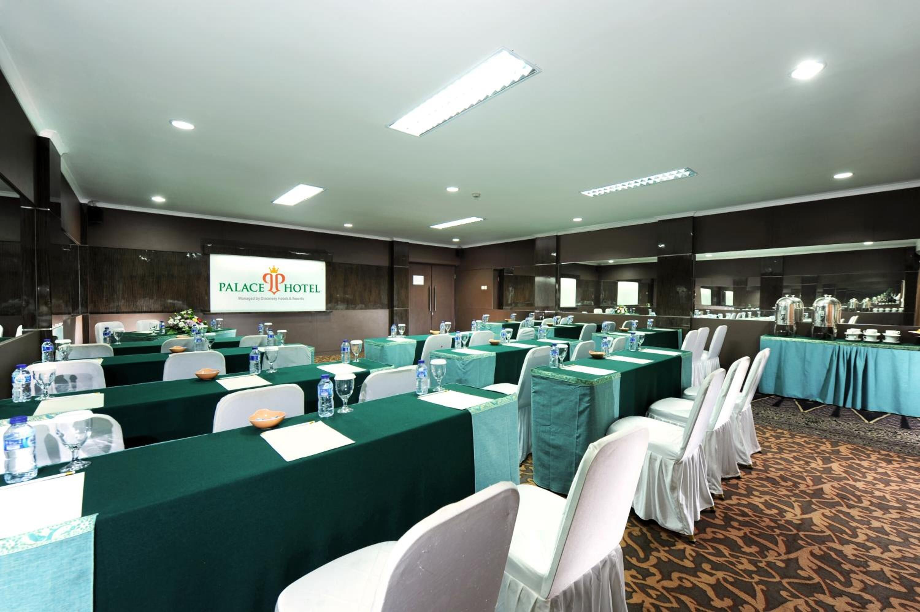 A conference room at the Palace Hotel with multiple tables set for a meeting, equipped with water bottles and nameplates.