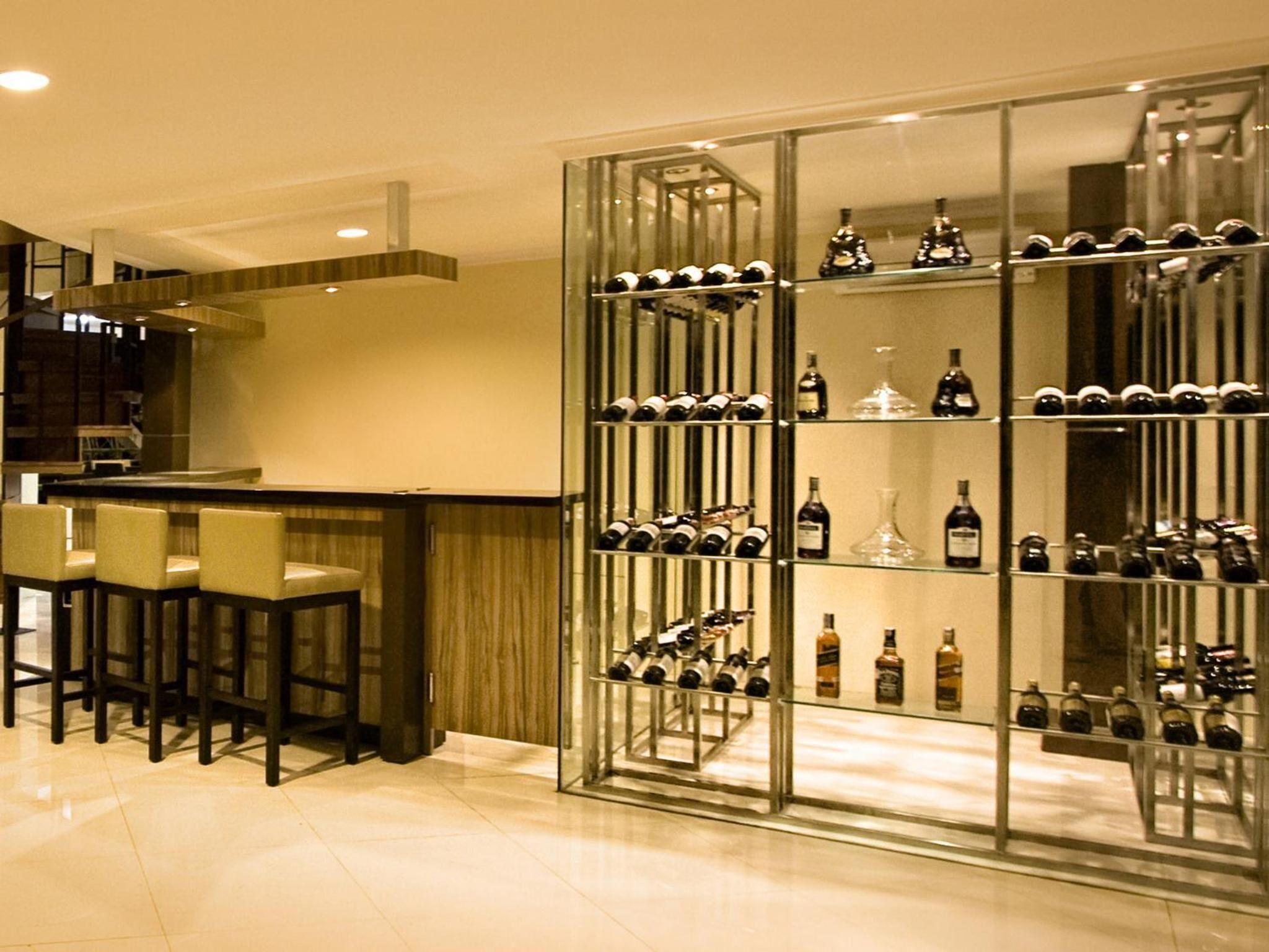 A modern bar area with a wine rack filled with bottles, a counter, and bar stools.