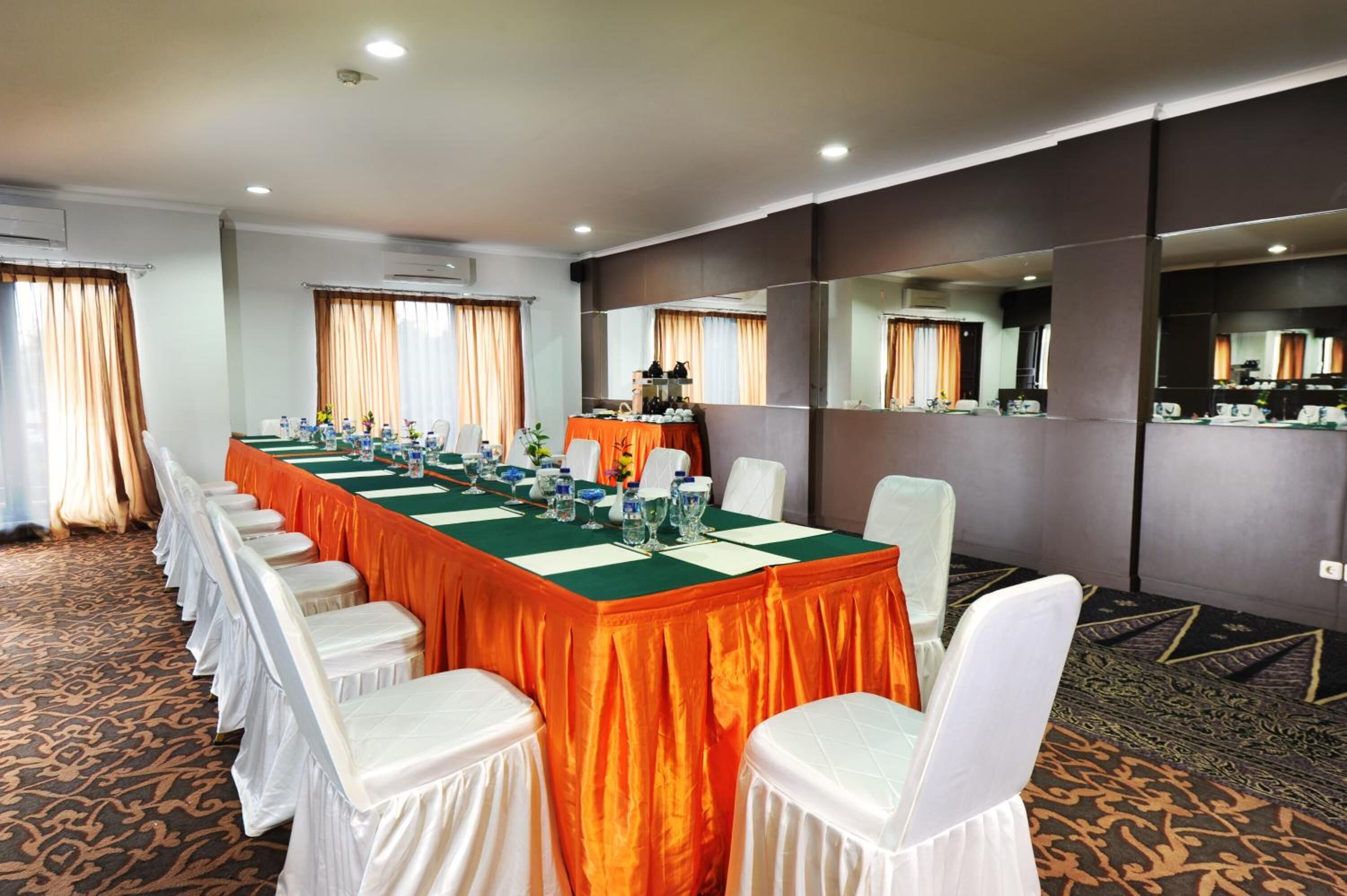 A conference room with a long table, white chairs, and a green tablecloth.