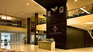 A modern hotel lobby with a reception desk, a large decorative rug, and a staircase leading to upper floors. - Palace Hotel (Cipanas)