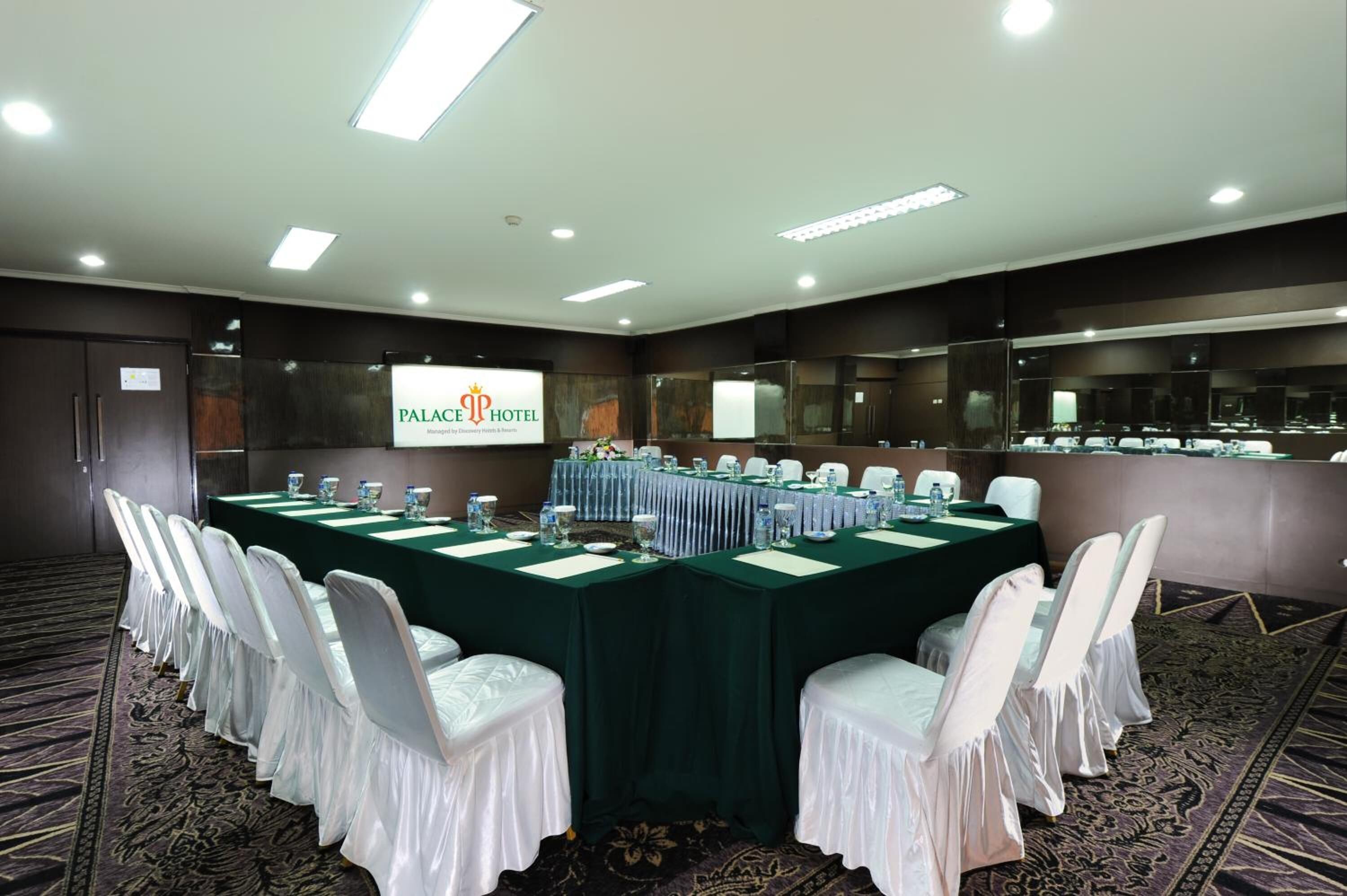 Una sala de conferencias con una larga mesa, sillas blancas y un cartel que dice "PALACE HOTEL".