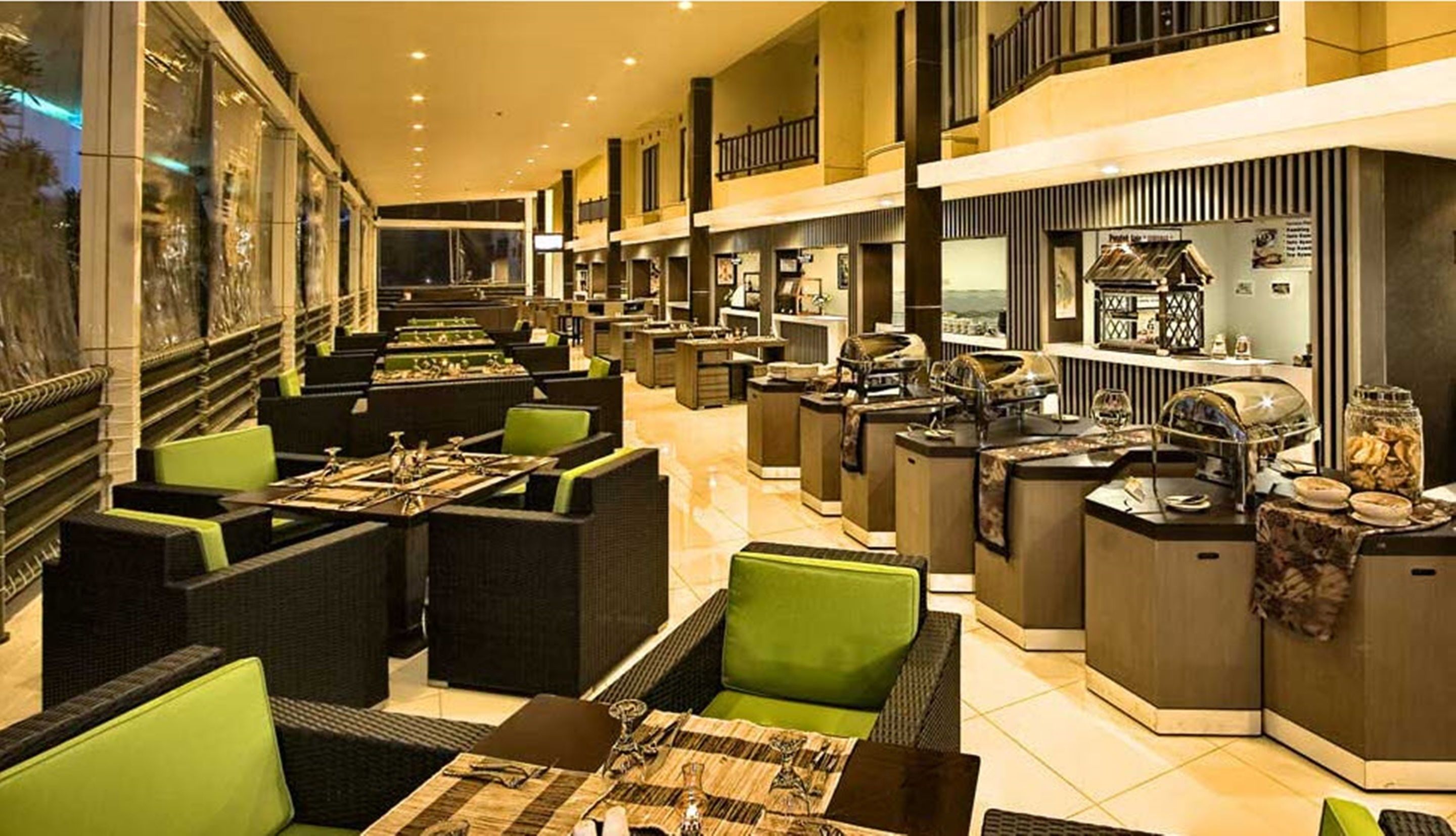 Um hall de hotel com várias áreas de estar, um balcão de buffet e uma escadaria para um andar superior.