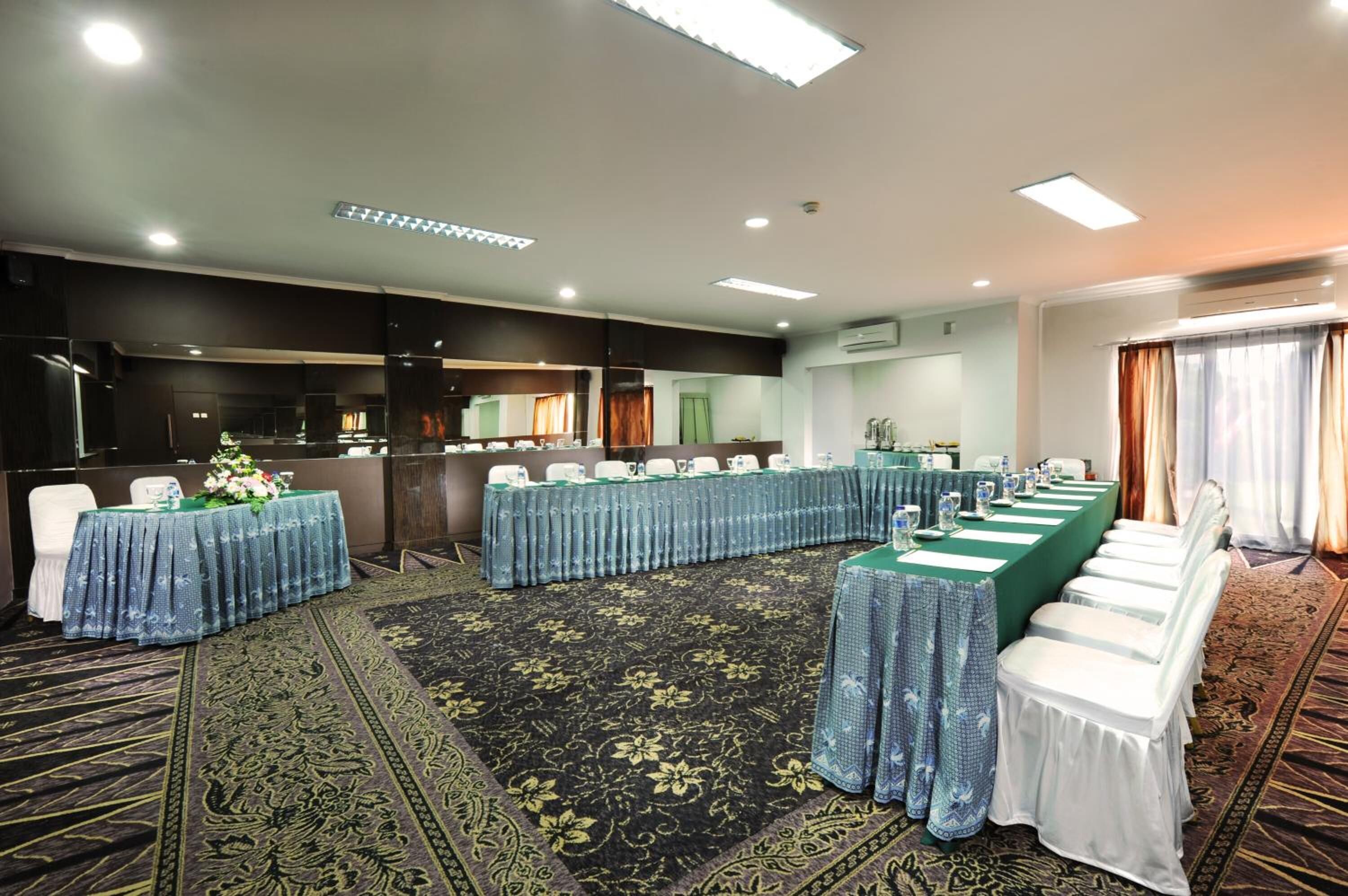 A conference room with a long table, chairs, and a carpeted floor.
