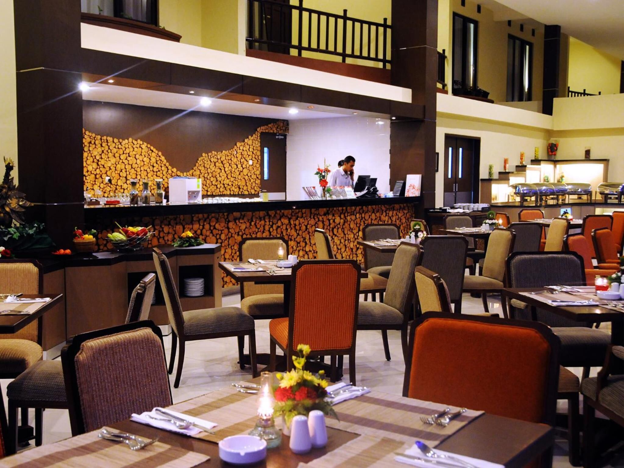 Un vestíbulo de hotel con una mesa de recepción, varias mesas de comedor y sillas.