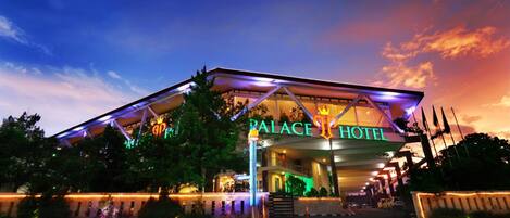 A hotel with a modern architectural design, featuring a prominent entrance and a sign that reads "PALACE HOTEL".