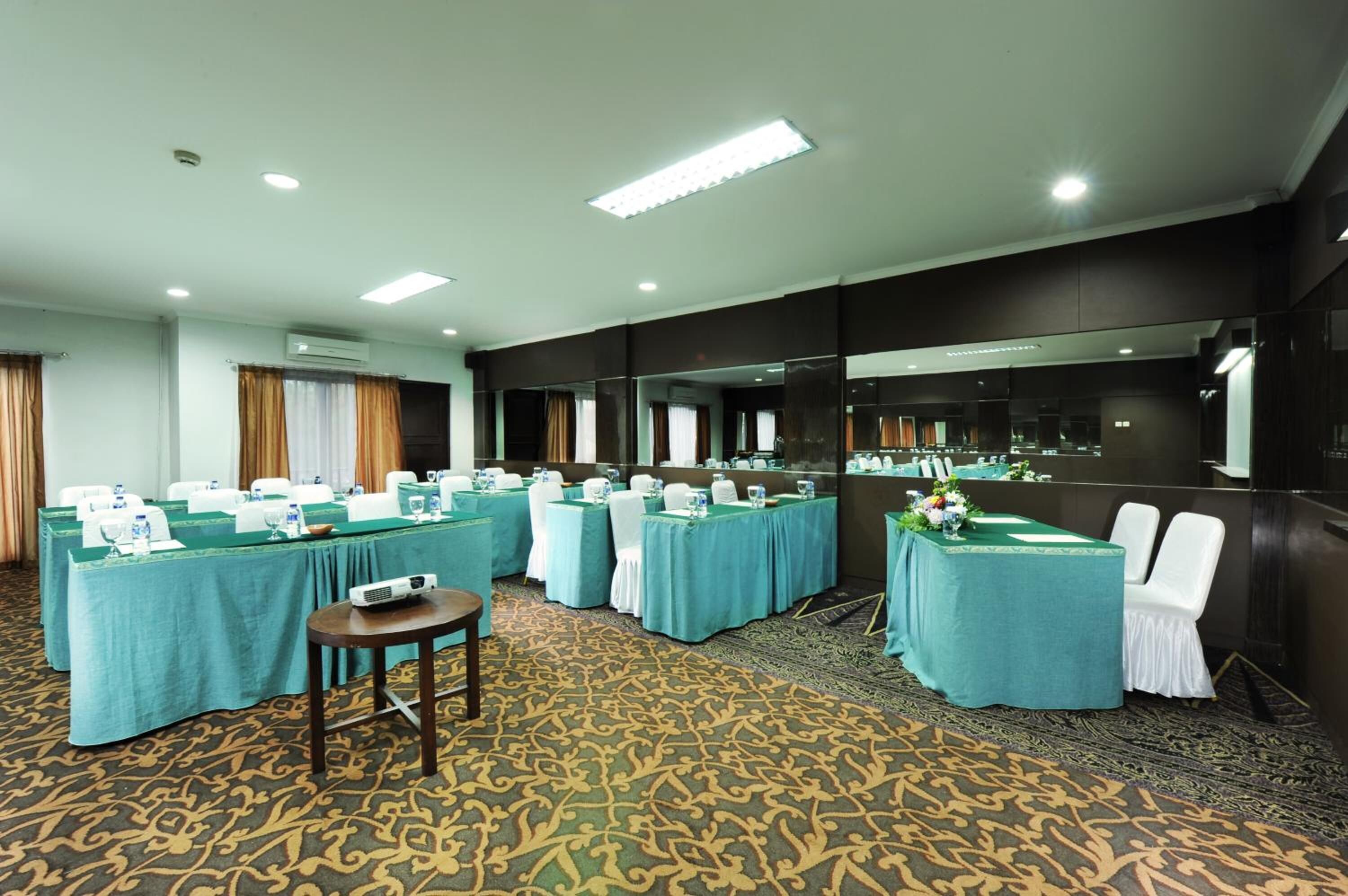 A conference room with multiple tables, chairs, and a projector.