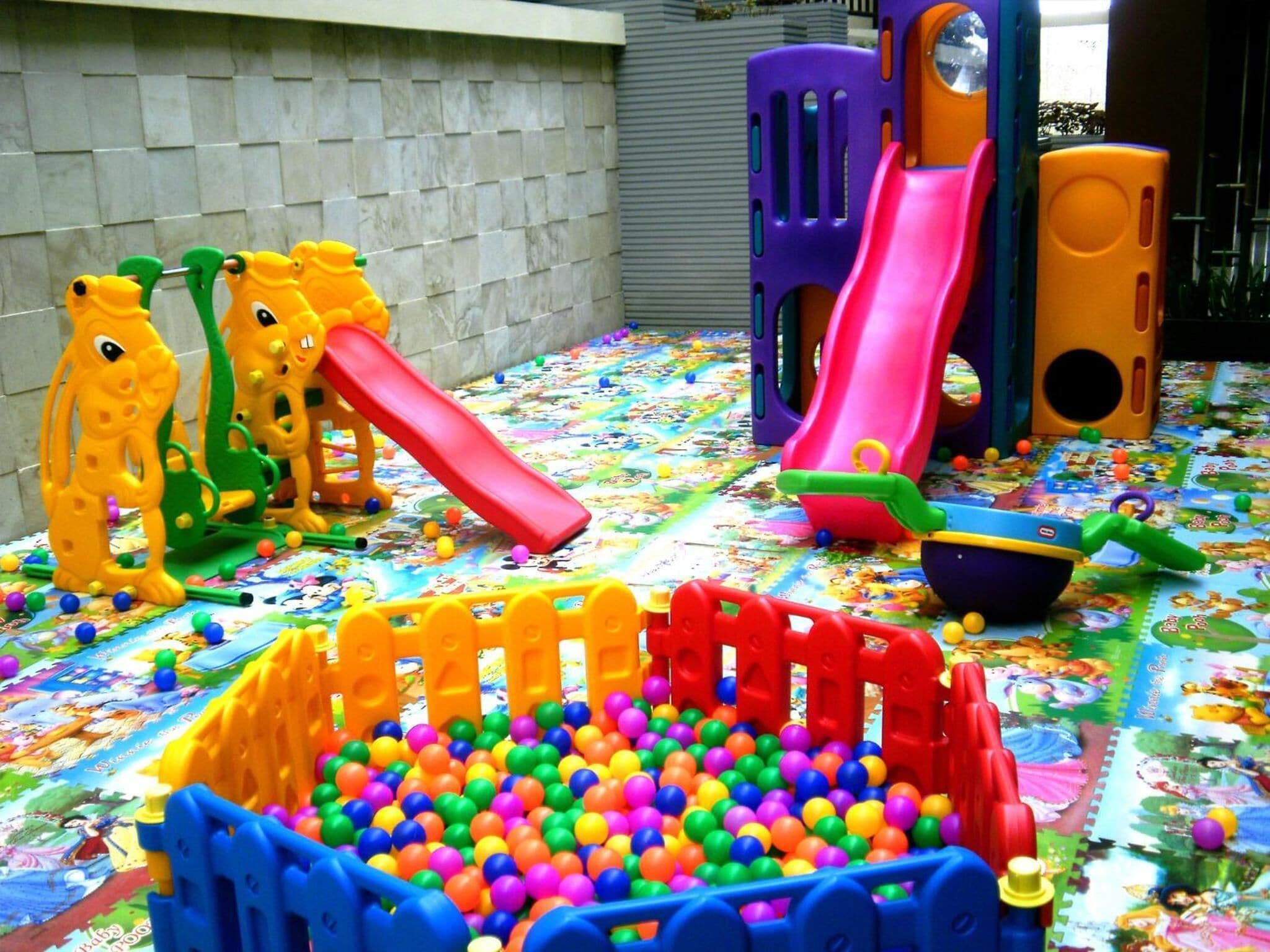 Un'area giochi colorata con scivoli, una piscina di palline e diversi giochi.
