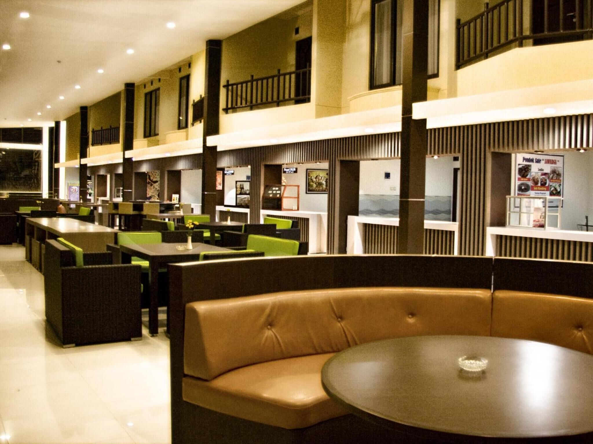 Un restaurant doté de nombreuses tables et de coins repas, d’un espace central avec une table ronde et offrant une vue sur la mer grâce à de grandes fenêtres.