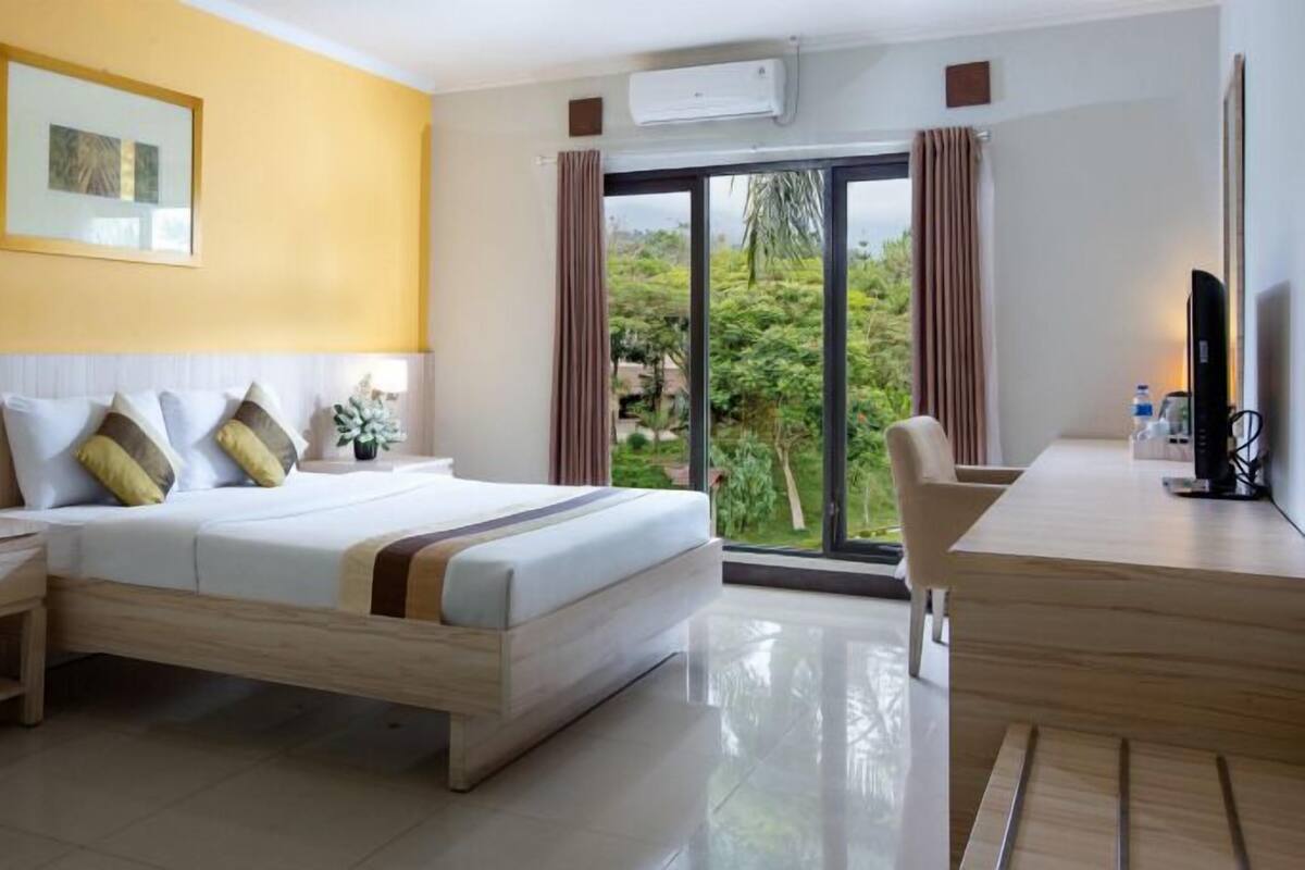 A hotel room with a bed, bedside tables, a desk, and a chair.