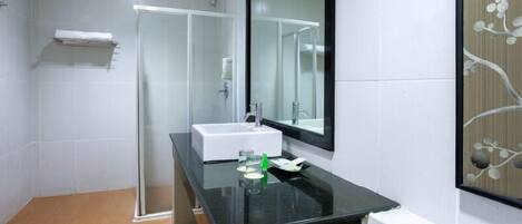 A modern bathroom with a glass shower enclosure, a white sink, and a large mirror.