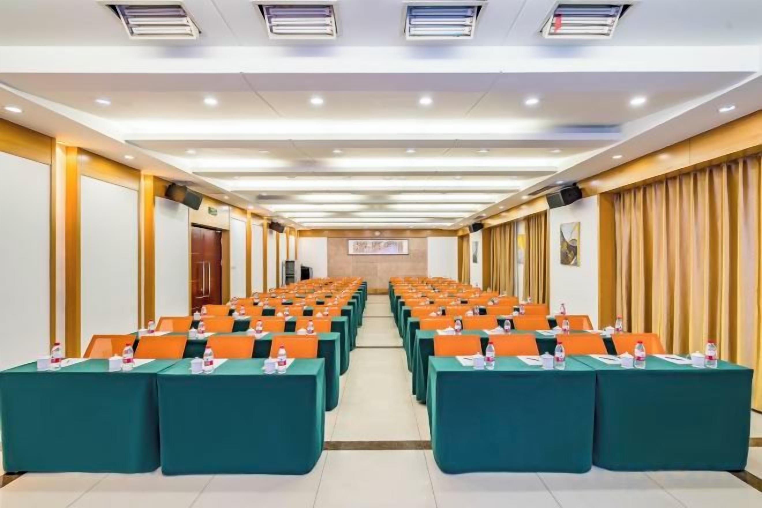 Un salón de conferencias con filas de mesas y sillas, un atril y una pantalla de proyección.
