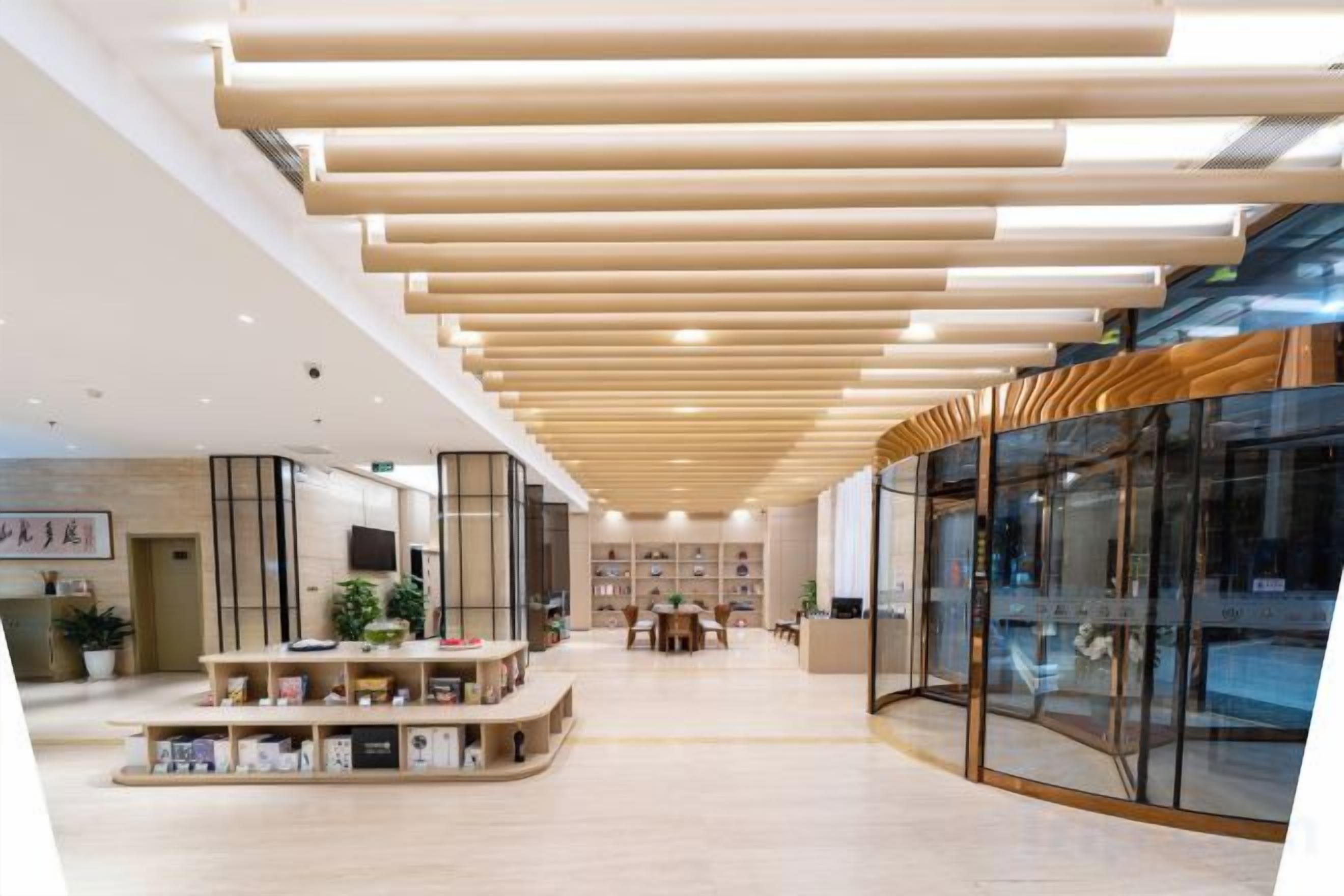 Un interior moderno con techo de madera, paredes de vidrio y una zona de estar central con plantas.