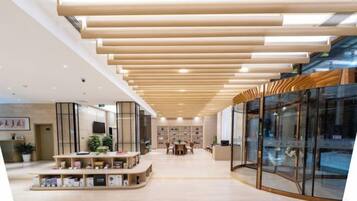 Un interior moderno con techo de madera, paredes de vidrio y una zona de estar central con plantas.