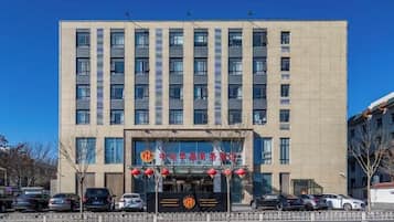 A multi-story building with a prominent entrance, several windows, and a clear sky.