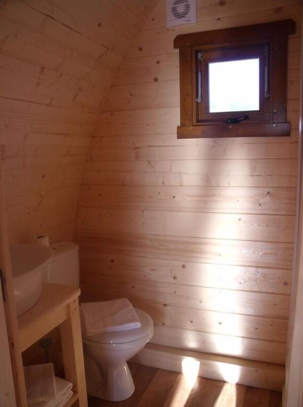 A small, wooden-paneled bathroom with a toilet, a shelf, and a window. - Le Domaine des Tuileries (Salins)